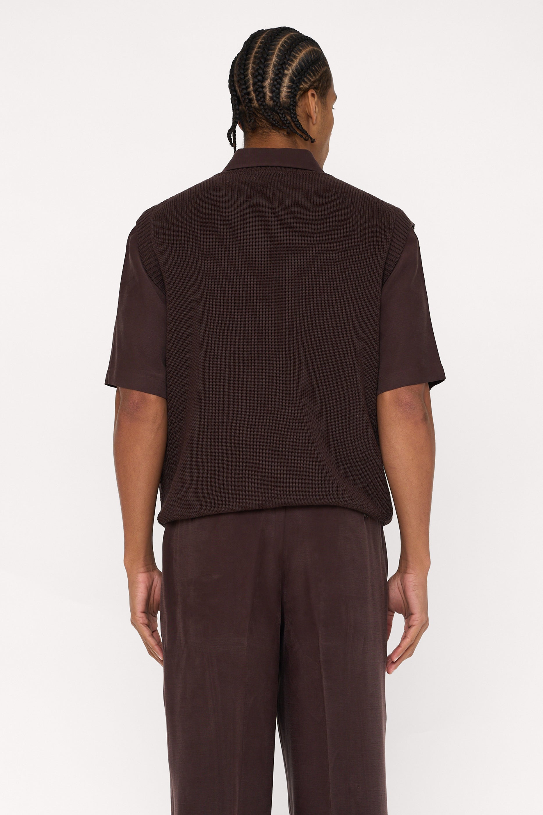 Back view of a maroon brown cotton and lyocell knit vest with a relaxed fit, worn over a brown relaxed shirt.