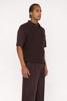 Right view of a maroon brown cotton and lyocell knit vest with a relaxed fit, worn over a brown relaxed shirt.